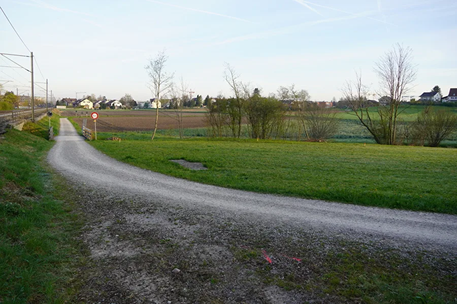 Der Hirzerenweg in Nänikon erhält einen neuen Deckbelag. Ein Schotterweg entlang einem Bahngleis.